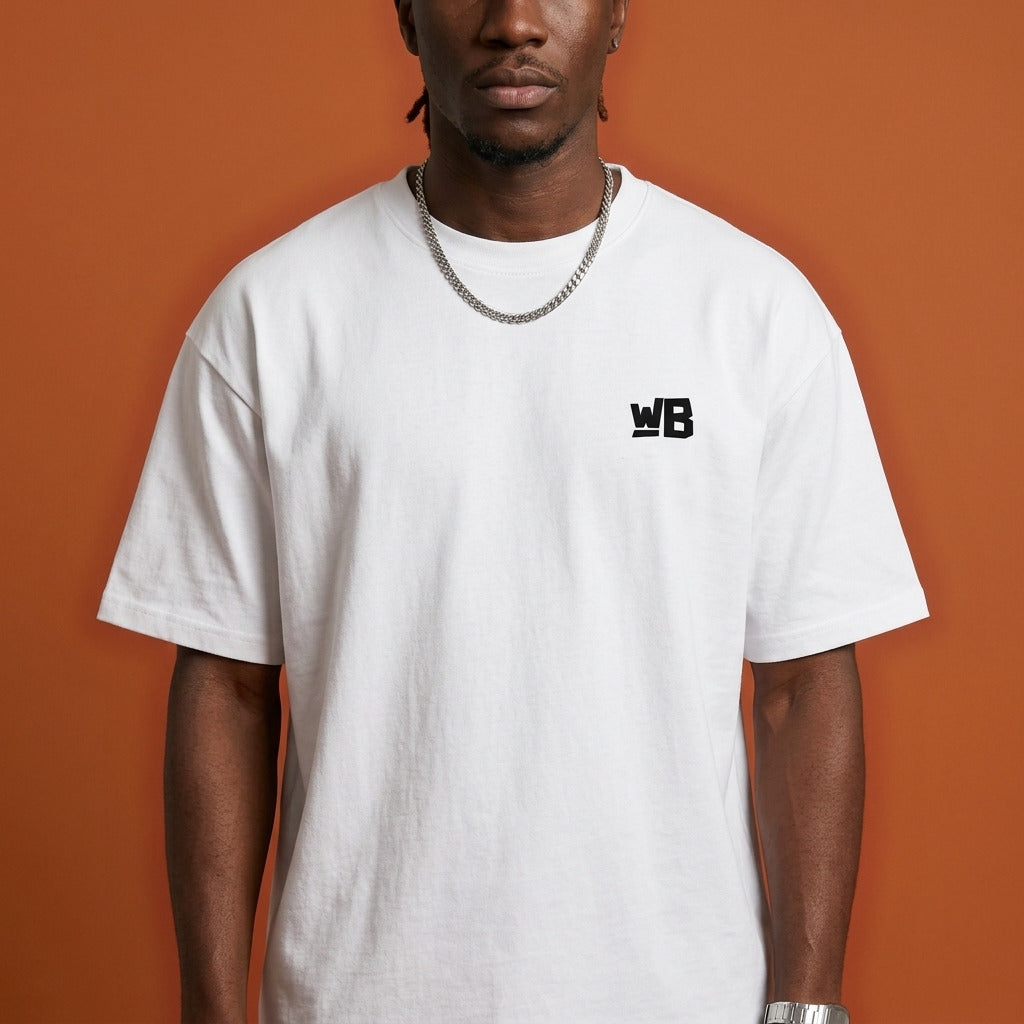Blackness Sankofa King Tee, white — chest detail close-up with WB monogram and ribbed collar, terracotta backdrop