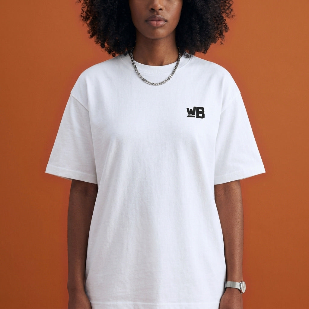 Blackness Sankofa Queen Tee, white — chest detail close-up with WB monogram and ribbed collar, terracotta backdrop