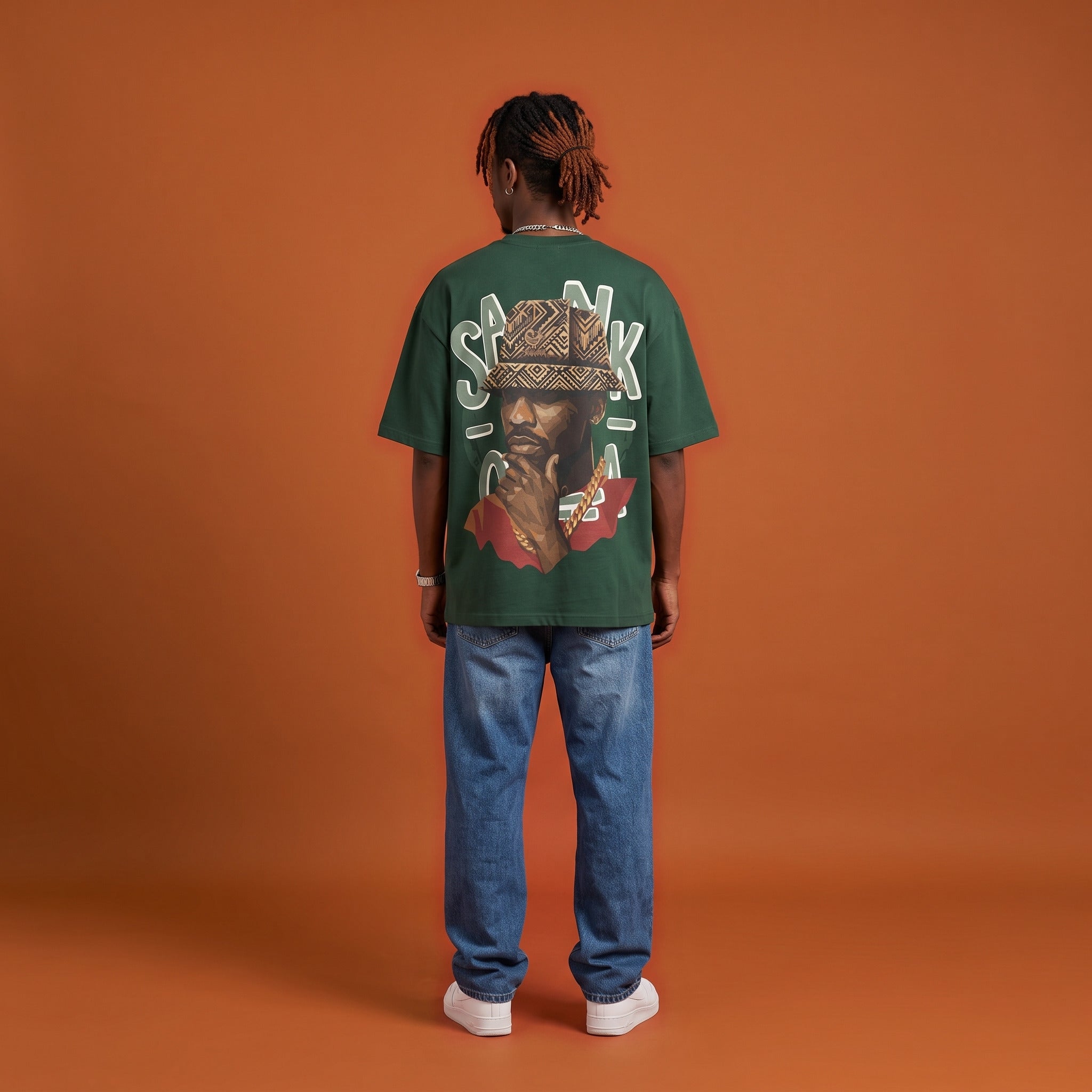 Blackness Sankofa King Tee, deep forest green, worn by a model — back view, Sankofa woven hat portrait print, terracotta backdrop