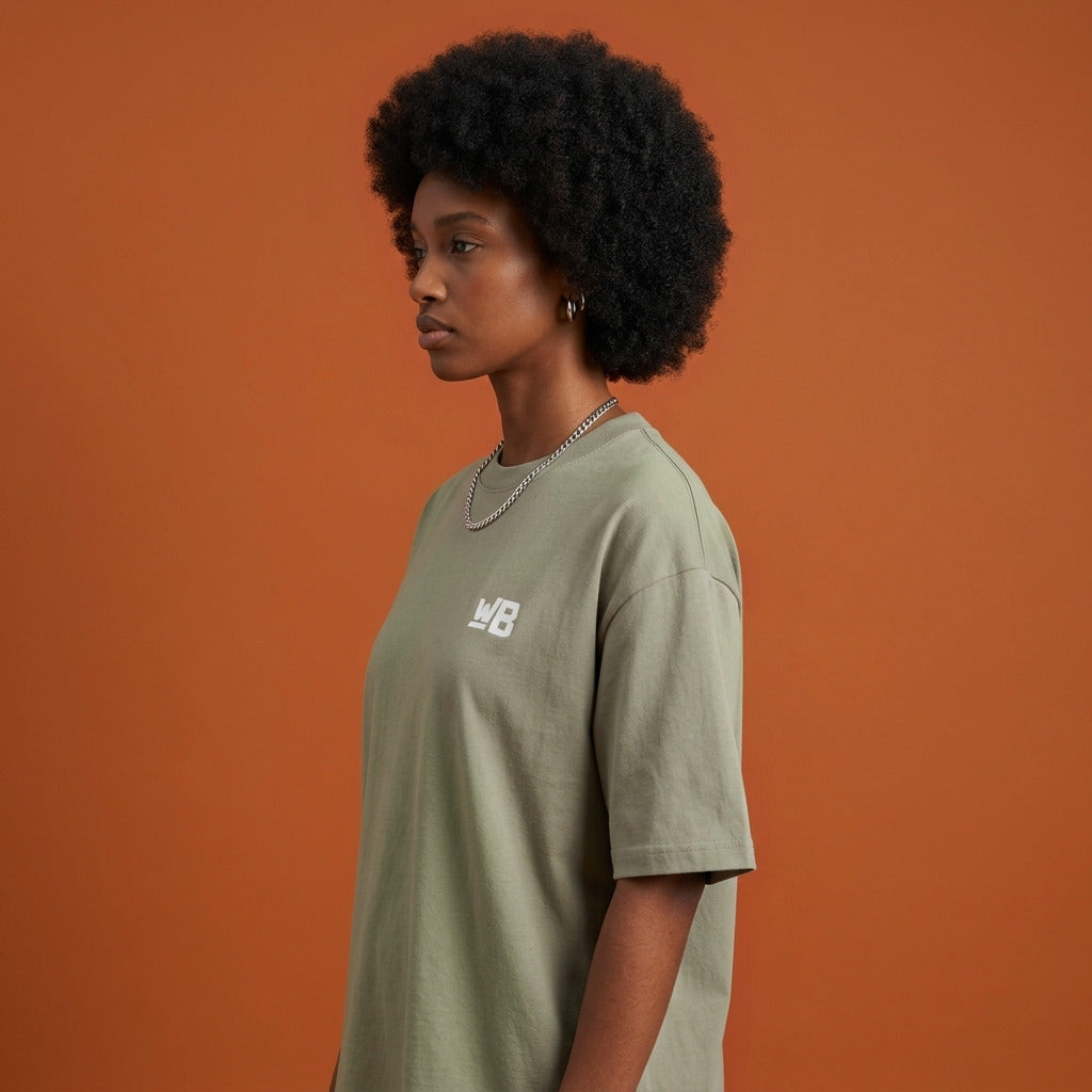 Blackness Sankofa Queen Tee, brown khaki — shoulder and collar detail, side view, terracotta backdrop
