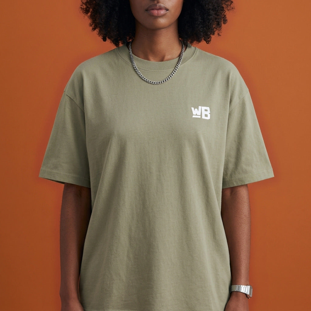 Blackness Sankofa Queen Tee, brown khaki — chest detail close-up with WB monogram and ribbed collar, terracotta backdrop