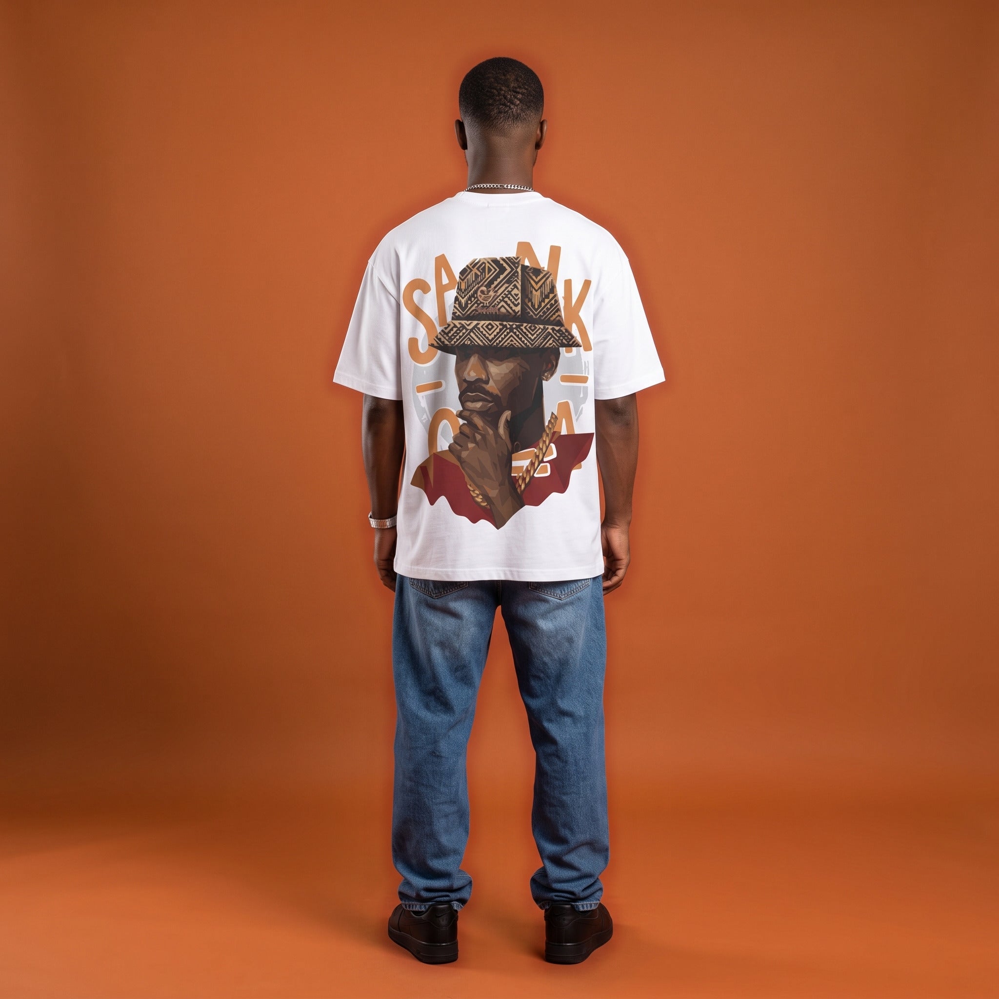 Blackness Sankofa King Tee, white, worn by a model — back view, Sankofa woven hat portrait print, terracotta backdrop