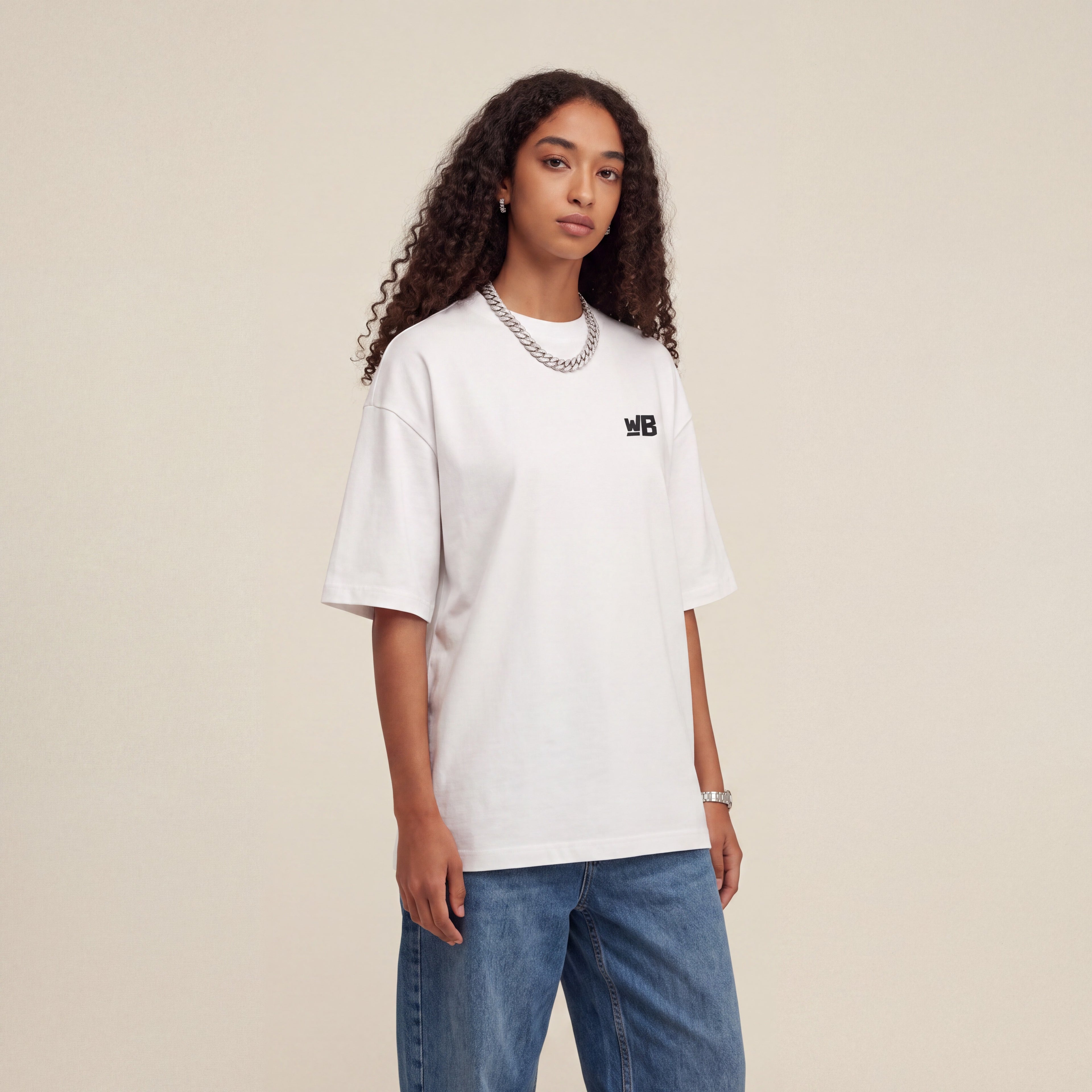 Base Blackness Tee White worn by model, front view with WB chest logo on warm ivory studio backdrop