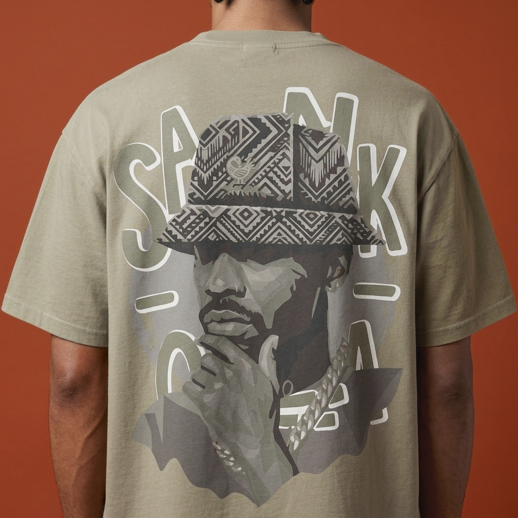 Blackness Sankofa King Tee, brown khaki — close-up of the Sankofa back print worn, terracotta backdrop