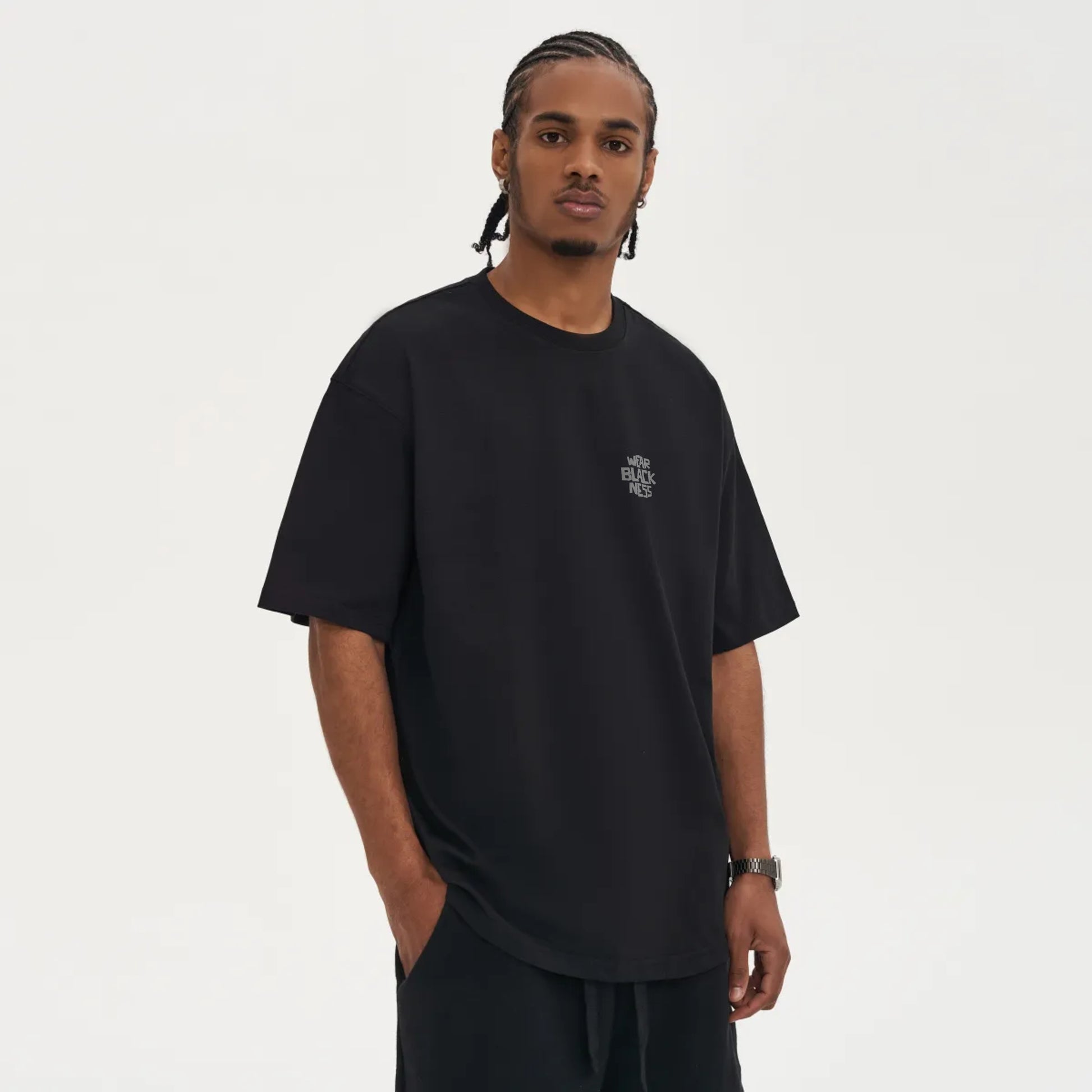 A person in front wearing the wear  Blackness Tee-shirt with print.