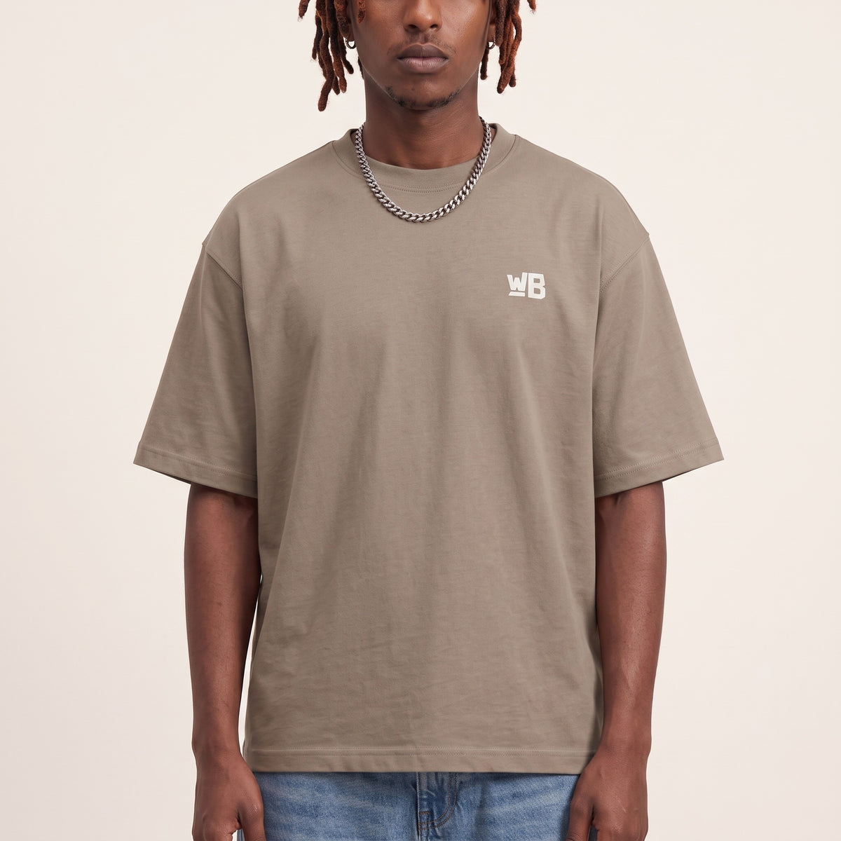 Base Blackness Tee Brown — close-up of the WB monogram chest logo and ribbed collar, oversized heavyweight cotton streetwear tee by We Are Blackness