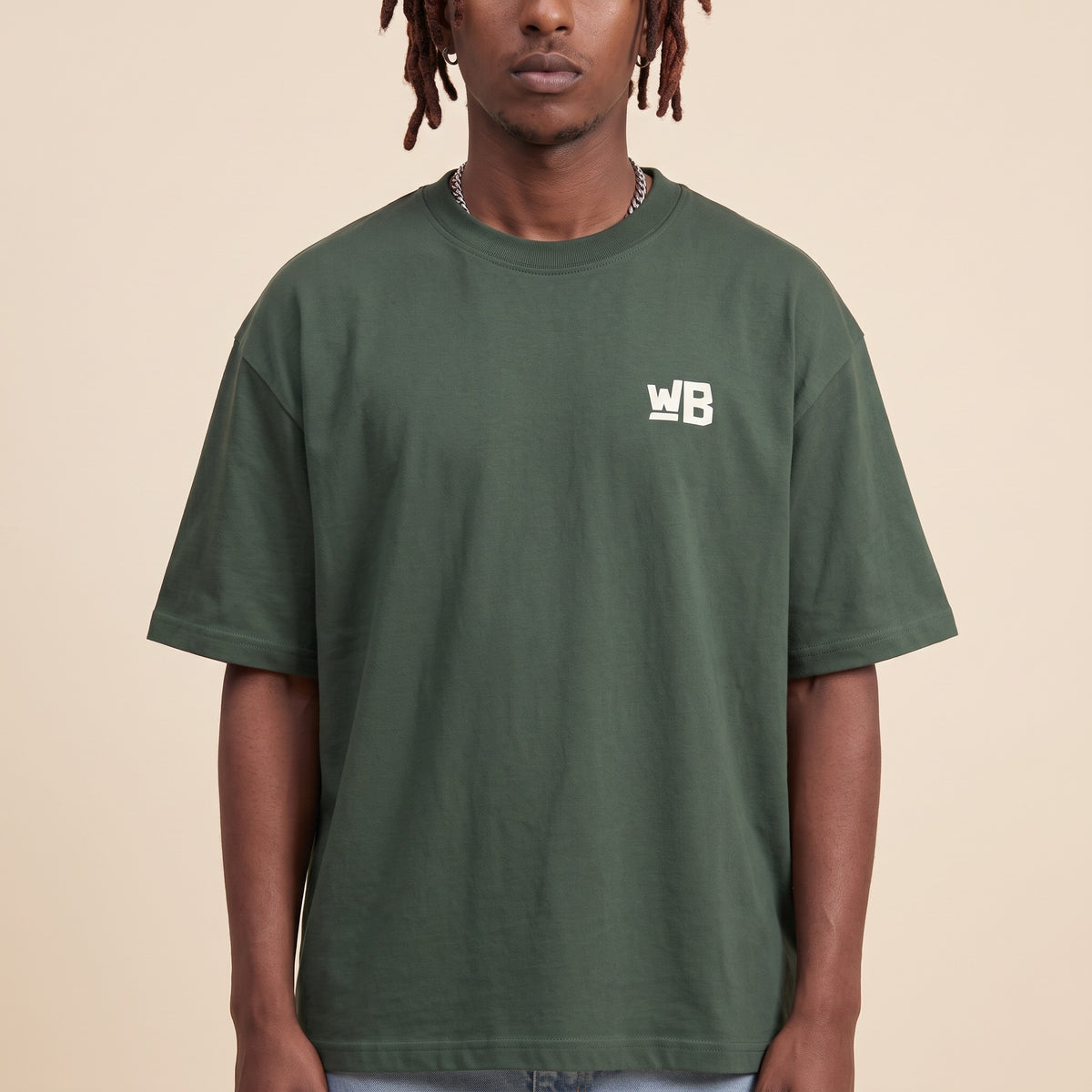 Blackness Emancipation Tee Cactus Green — close-up of the WB monogram chest logo and ribbed collar, oversized heavyweight cotton streetwear tee by We Are Blackness