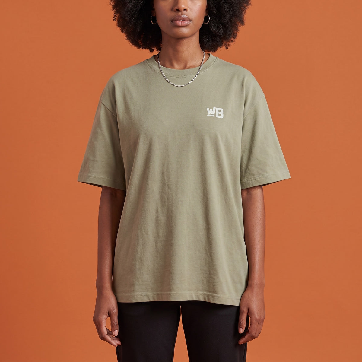Blackness Libation Tee Brown Khaki — close-up of the WB monogram chest logo and ribbed collar, oversized heavyweight cotton streetwear tee by We Are Blackness
