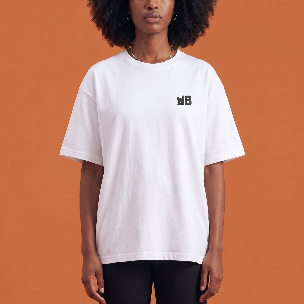Blackness Libation Tee White — close-up of the WB monogram chest logo and ribbed collar, oversized heavyweight cotton streetwear tee by We Are Blackness