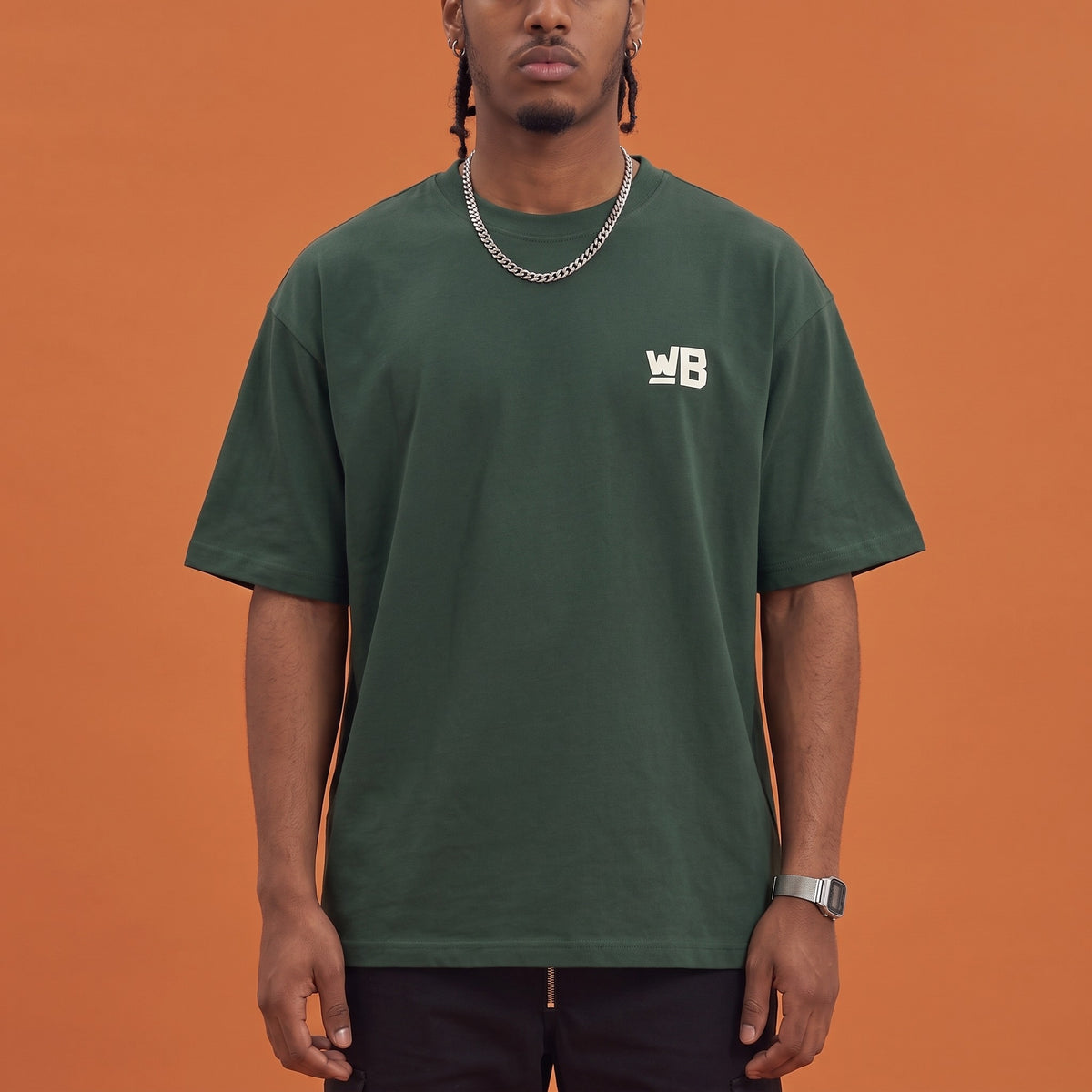 Blackness Mawon Tee Forest Green — close-up of the WB monogram chest logo and ribbed collar, oversized heavyweight cotton streetwear tee by We Are Blackness