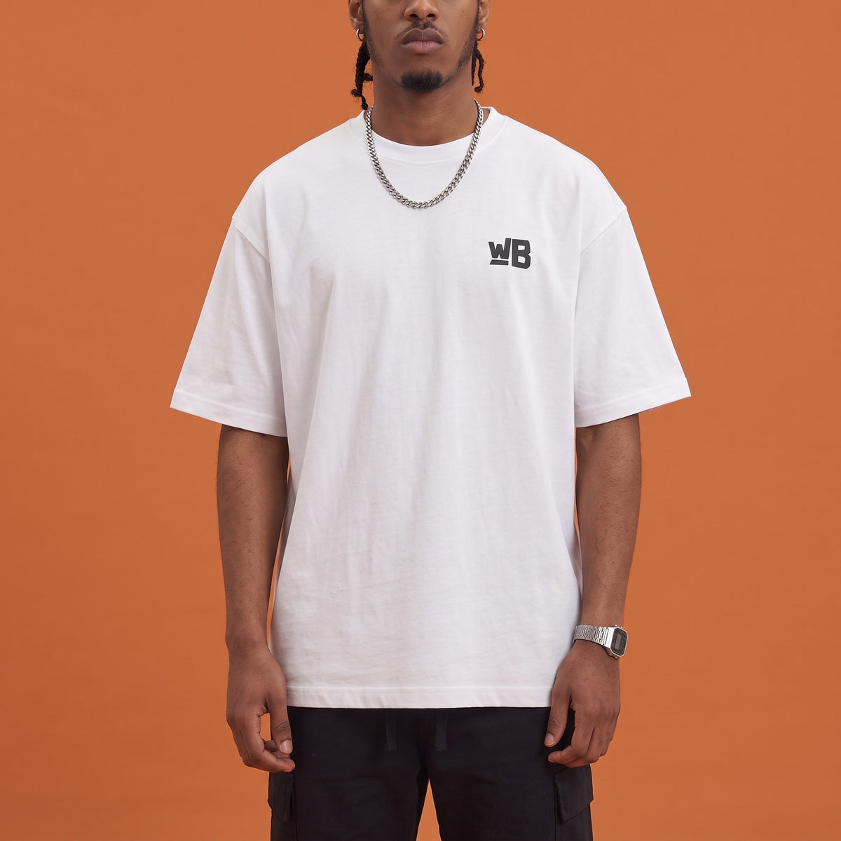 Blackness Mawon Tee White — close-up of the WB monogram chest logo and ribbed collar, oversized heavyweight cotton streetwear tee by We Are Blackness