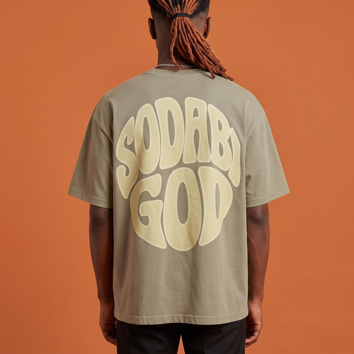 Blackness Sodabi Tee Brown Khaki — close-up of the SODABI GOD bubble-letter back print worn on the back, oversized heavyweight cotton streetwear tee by We Are Blackness