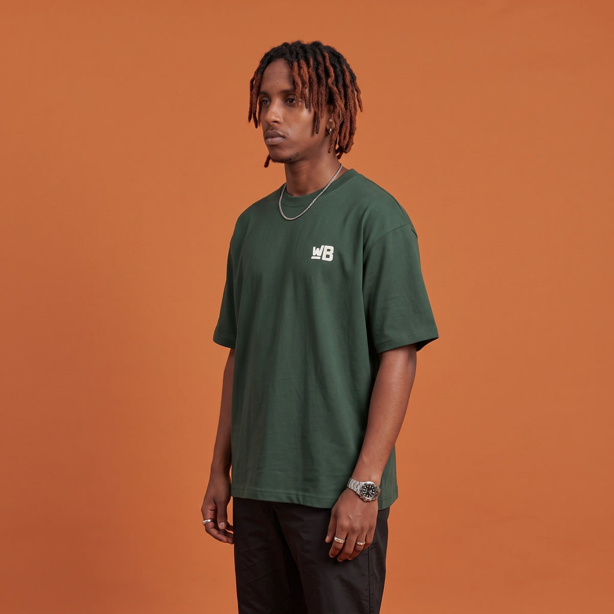 Blackness Sodabi Tee Forest Green — side view of the drop-shoulder sleeve and boxy oversized fit, oversized heavyweight cotton streetwear tee by We Are Blackness