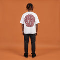 Blackness Sodabi Tee, white, worn by a model — back view, SODABI GOD bubble lettering print, terracotta-orange studio backdrop