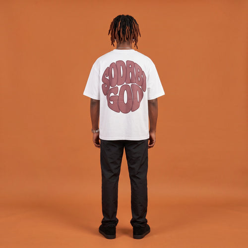 Blackness Sodabi Tee, white, worn by a model — back view, SODABI GOD bubble lettering print, terracotta-orange studio backdrop