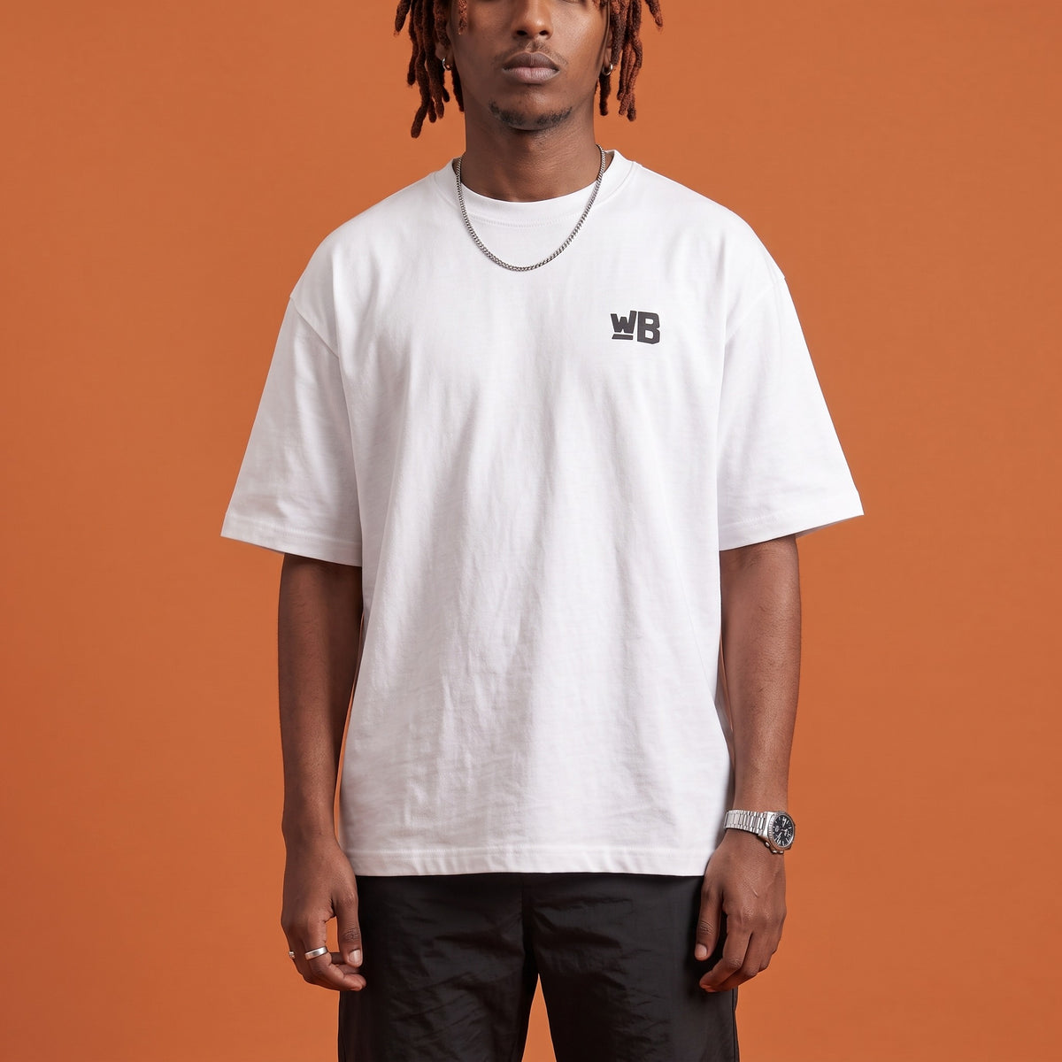 Blackness Sodabi Tee White — close-up of the WB monogram chest logo and ribbed collar, oversized heavyweight cotton streetwear tee by We Are Blackness