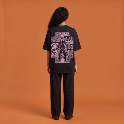 Blackness Solitude Tee, black, worn by a model — back view, Solitude portrait block print, terracotta-orange studio backdrop