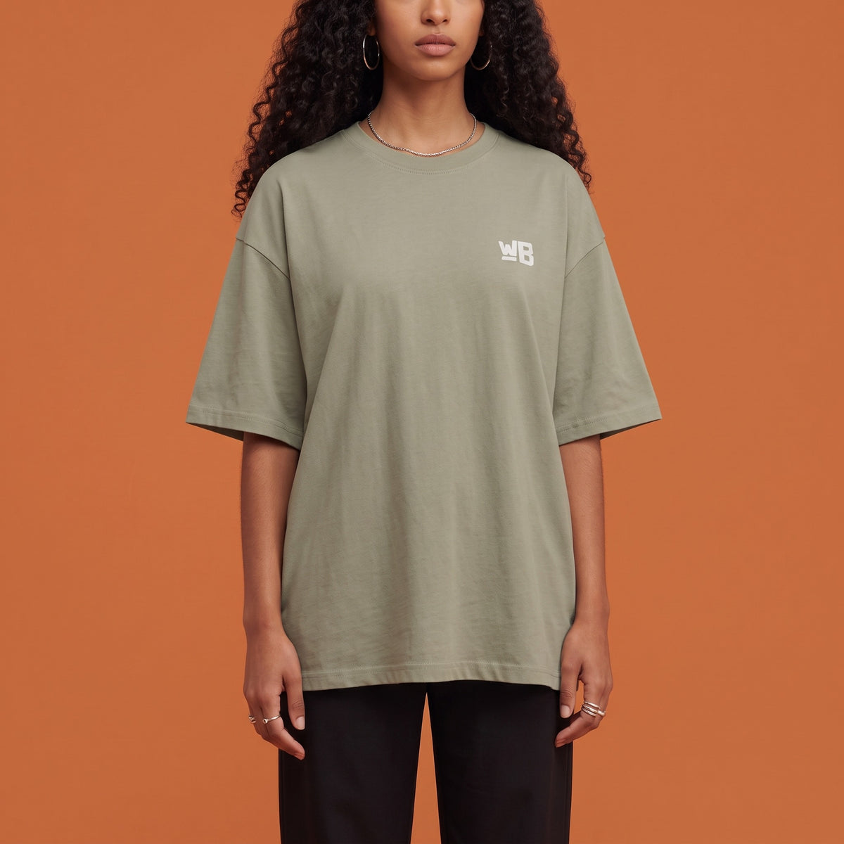 Blackness Solitude Tee Brown Khaki — close-up of the WB monogram chest logo and ribbed collar, oversized heavyweight cotton streetwear tee by We Are Blackness