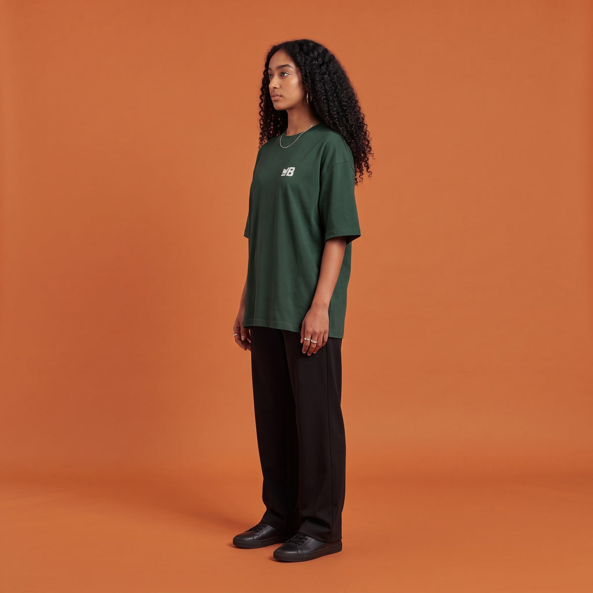Blackness Solitude Tee Forest Green — side view of the drop-shoulder sleeve and boxy oversized fit, oversized heavyweight cotton streetwear tee by We Are Blackness