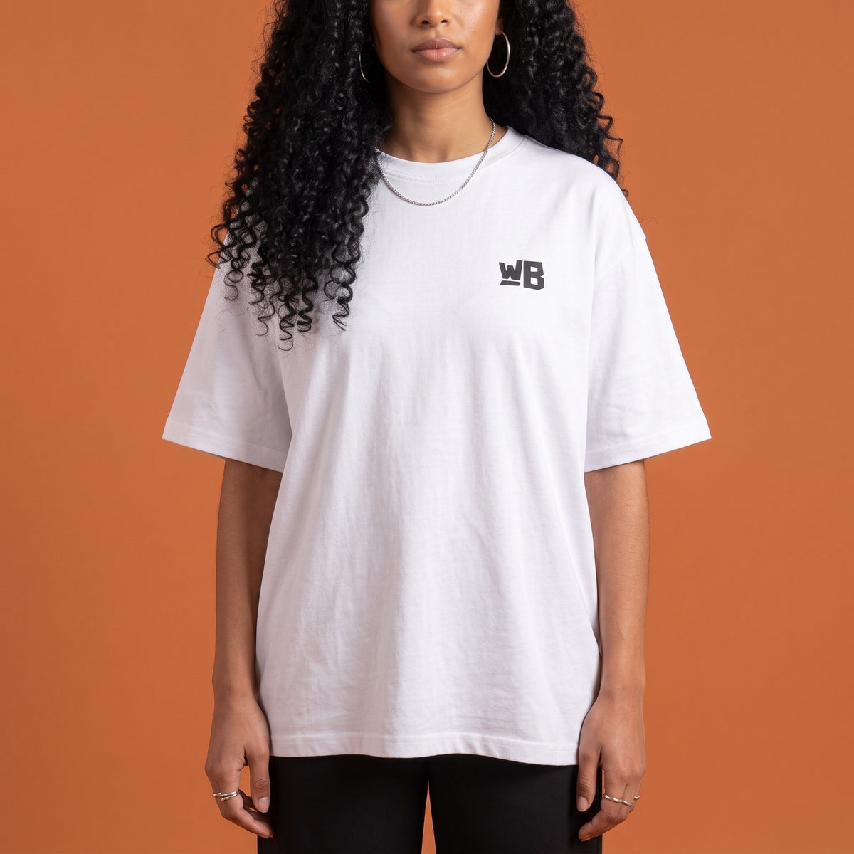 Blackness Solitude Tee White — close-up of the WB monogram chest logo and ribbed collar, oversized heavyweight cotton streetwear tee by We Are Blackness