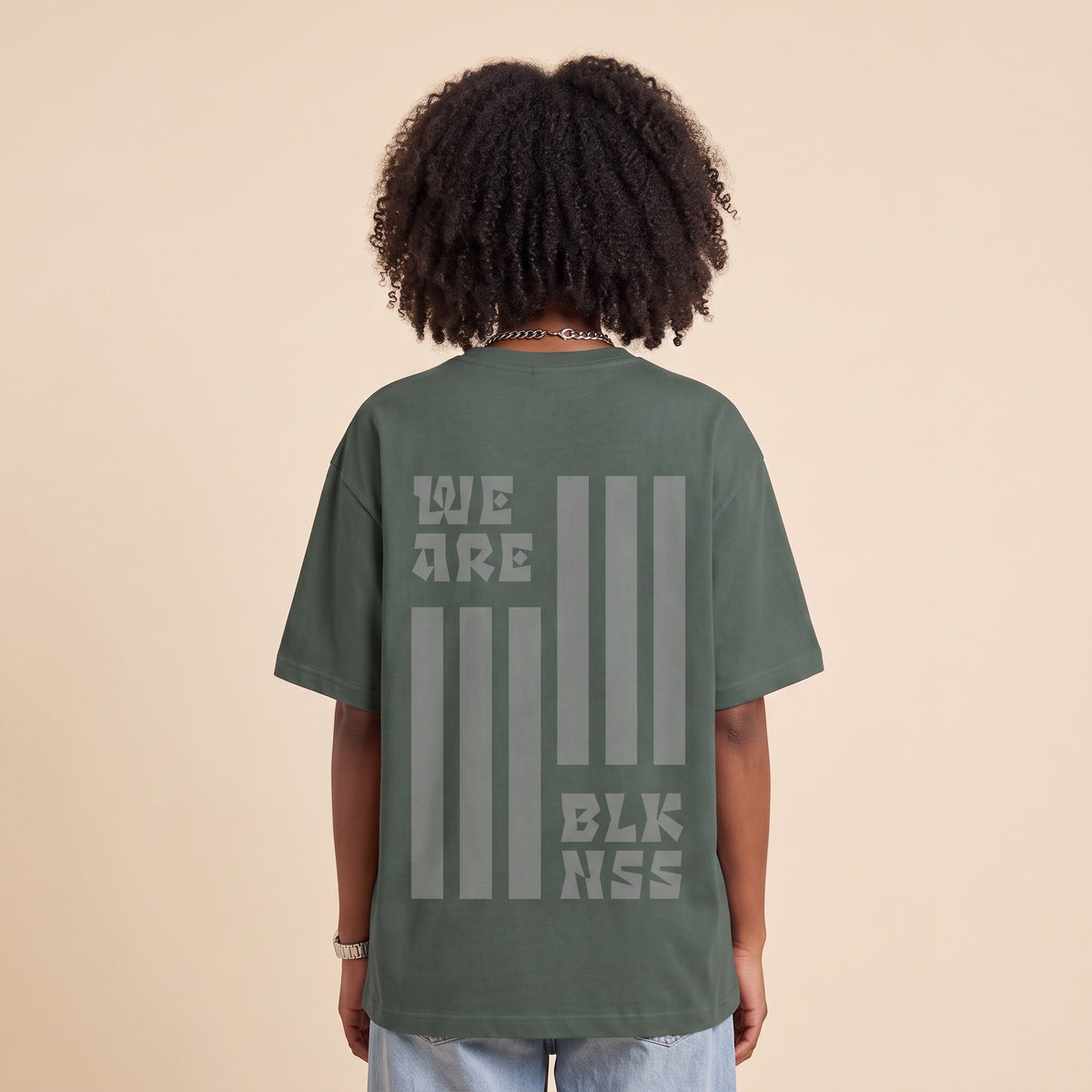 Blackness WABLKNSS Tee Green — close-up of the We Are BLK NSS stripe graphic back print worn on the back, oversized heavyweight cotton streetwear tee by We Are Blackness