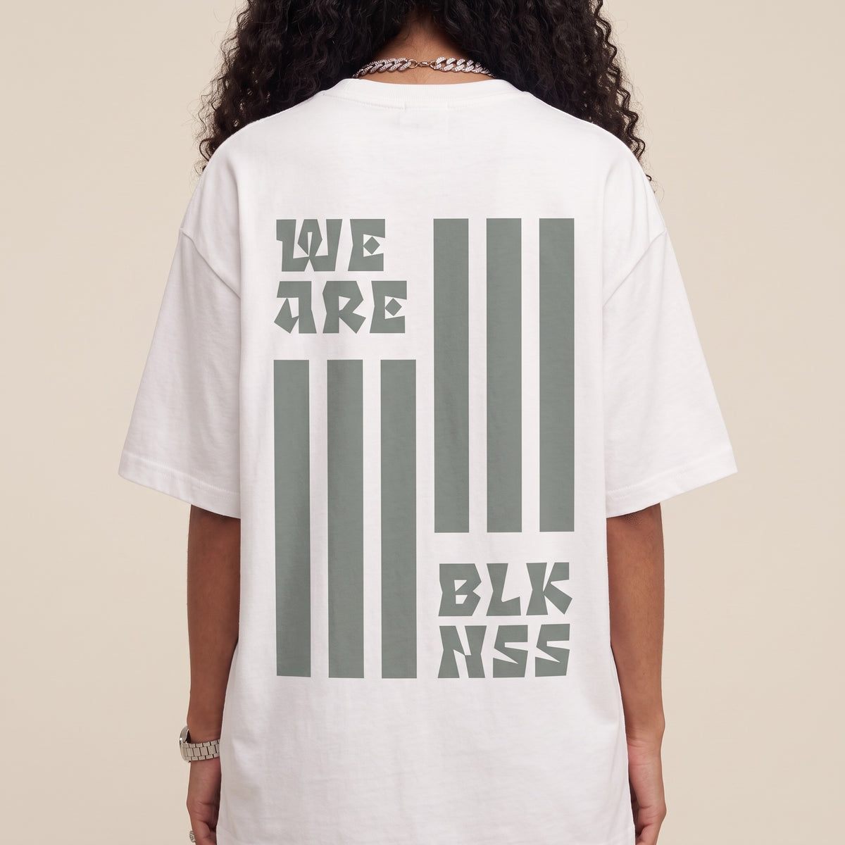 Blackness WABLKNSS Tee White — close-up of the We Are BLK NSS stripe graphic back print worn on the back, oversized heavyweight cotton streetwear tee by We Are Blackness