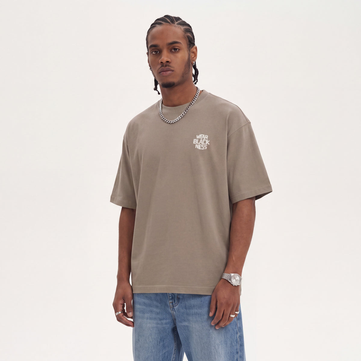 Wear Blackness Tee Brown worn by model, front view with Wear Blackness chest print on warm ivory studio backdrop