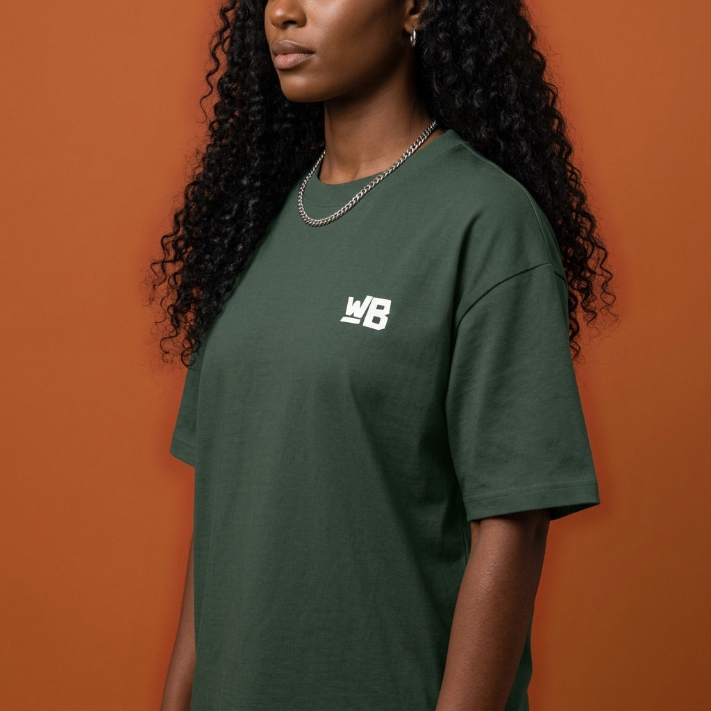 Blackness Sankofa Queen Tee, deep forest green — shoulder and collar detail, side view, terracotta backdrop