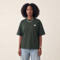 Base Blackness Tee Green worn by model, front view with WB chest logo on warm ivory studio backdrop