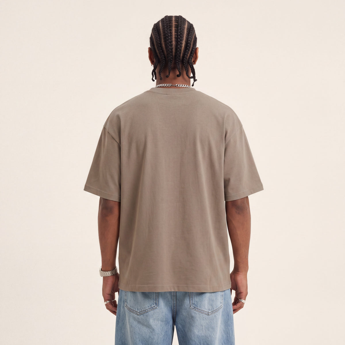 Wear Blackness Tee Brown worn by model, back view showing the clean plain back on warm ivory studio backdrop