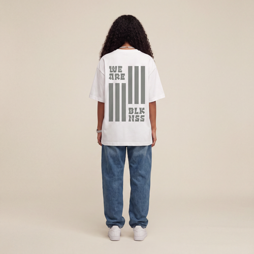 Blackness WABLKNSS Tee White worn by model, back print view on beige studio backdrop