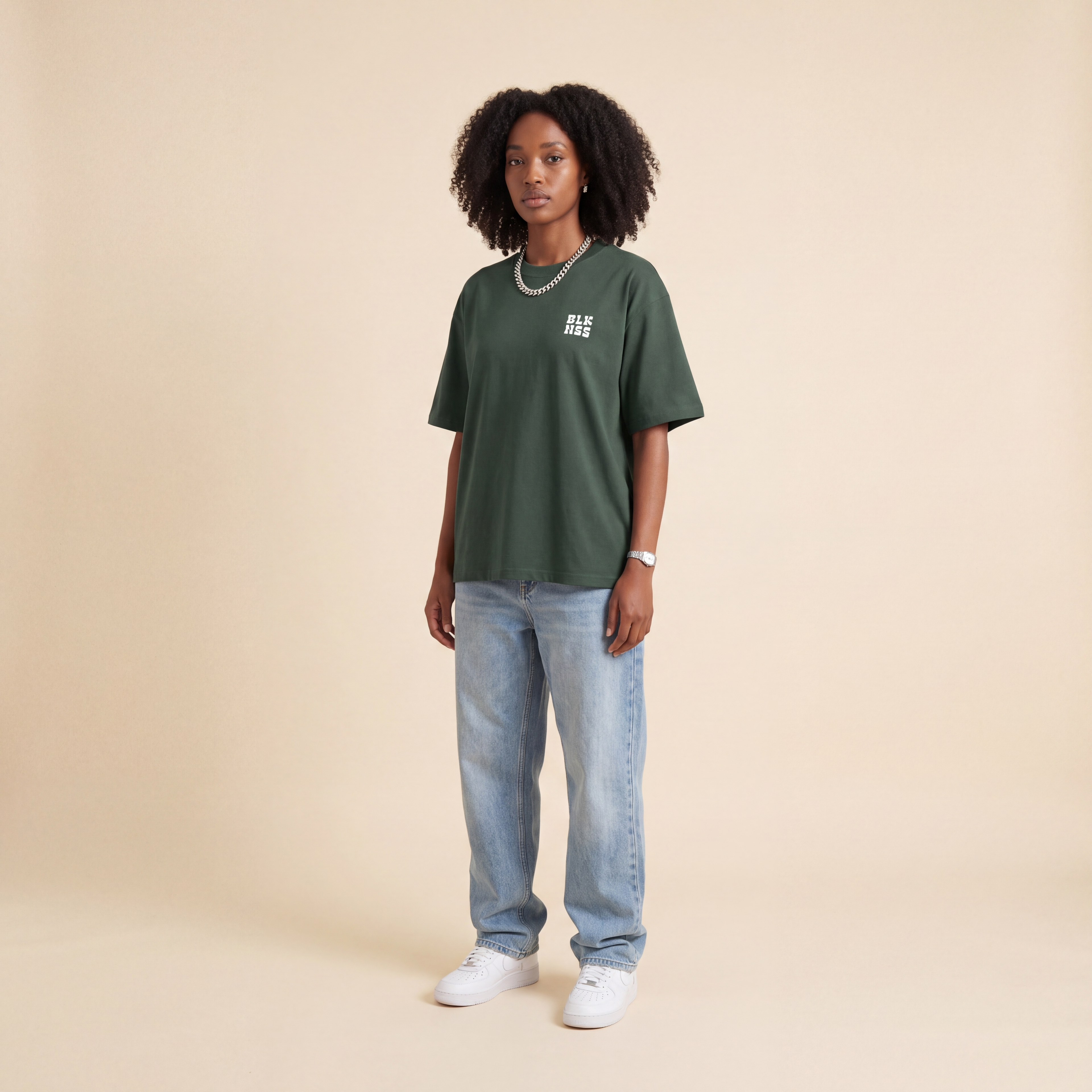 Blackness WABLKNSS Tee Green worn by model, front view on beige studio backdrop
