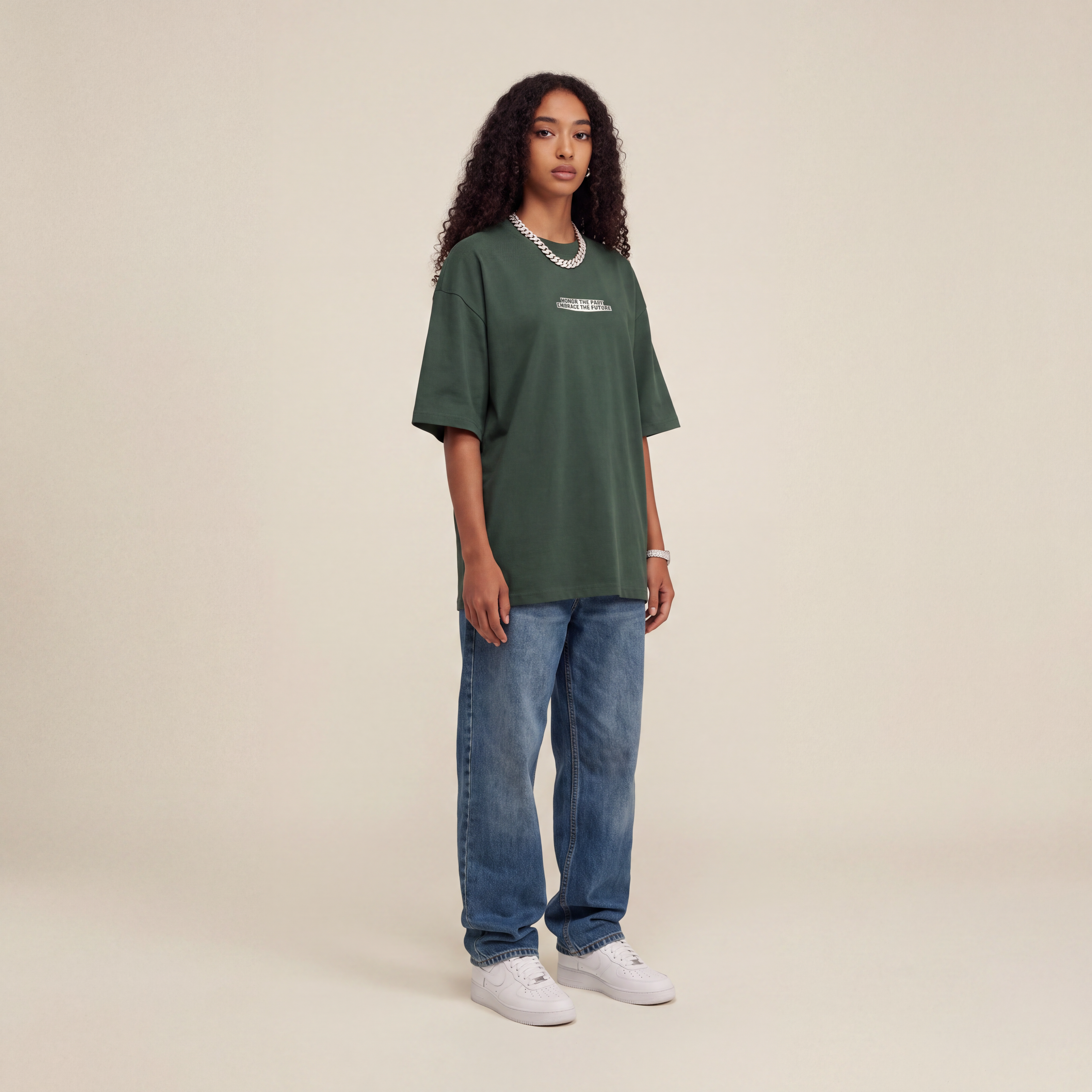Blackness Honor & Embrace Tee Cactus Green worn by model, front view with the Honor The Past Embrace The Future chest print on beige studio backdrop