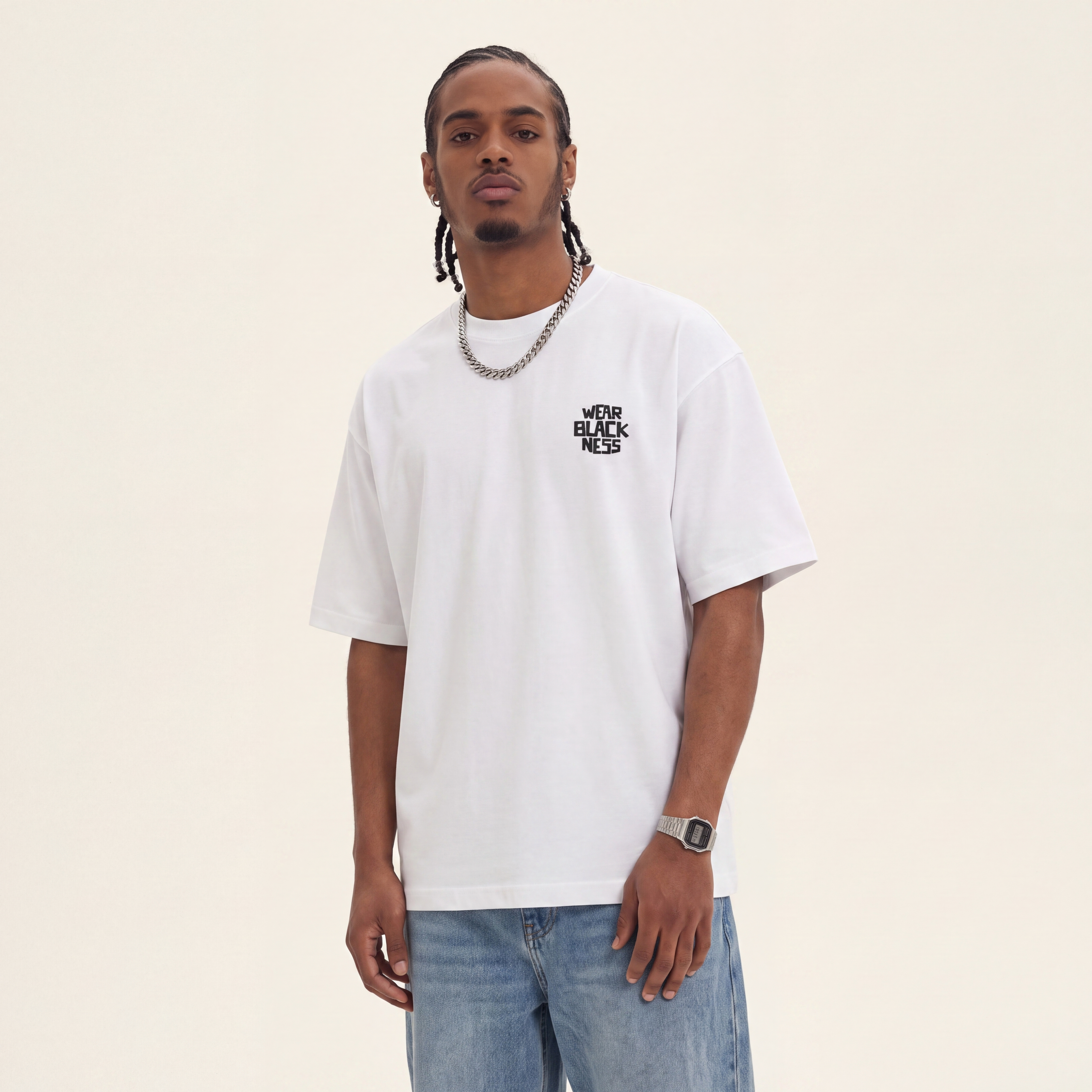 Wear Blackness Tee White worn by model, front view with Wear Blackness chest print on warm ivory studio backdrop