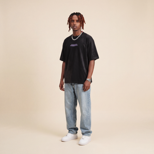 Blackness Honor & Embrace Tee Black worn by model, front view with the Honor The Past Embrace The Future chest print on beige studio backdrop