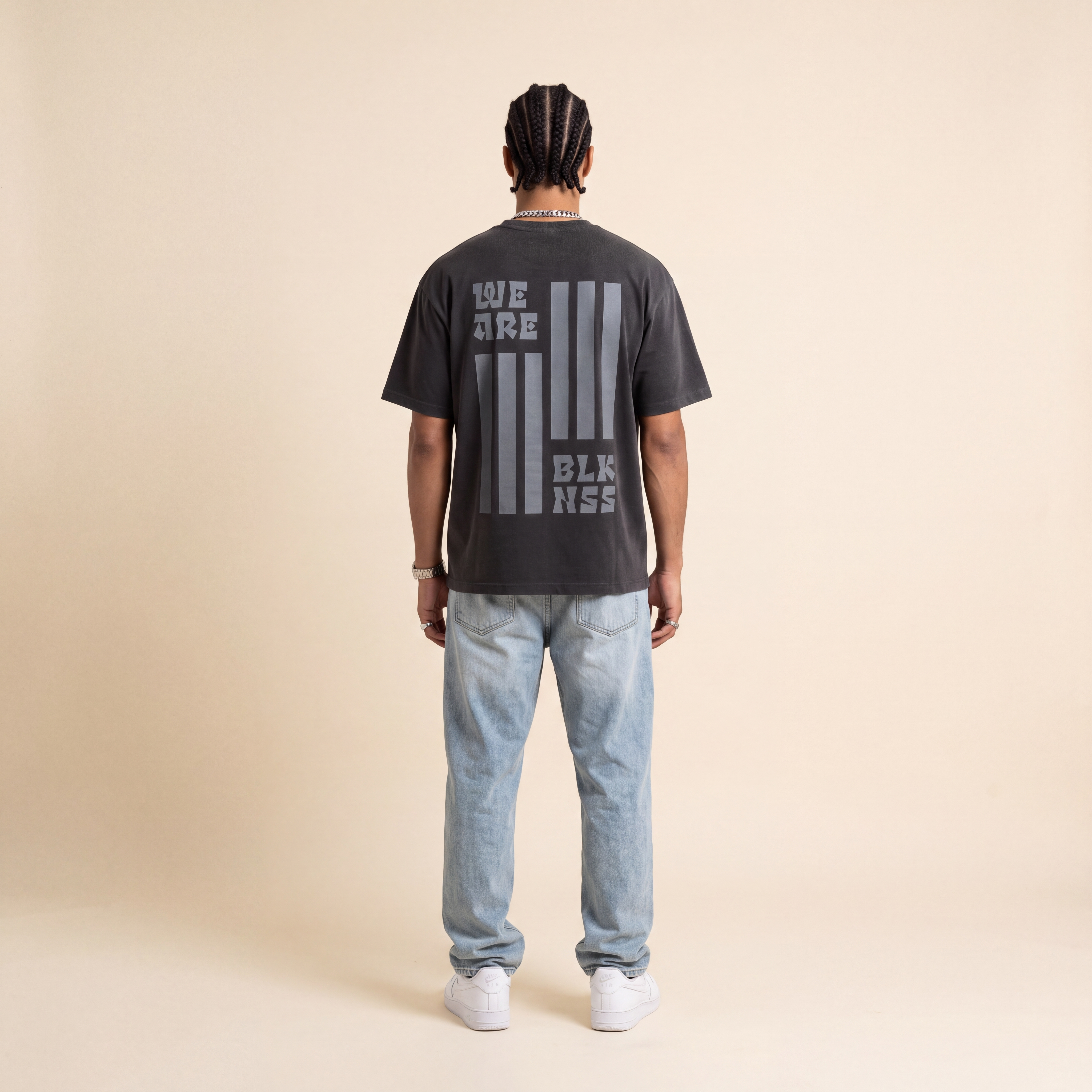 Blackness WABLKNSS Tee Black worn by model, back print view on beige studio backdrop