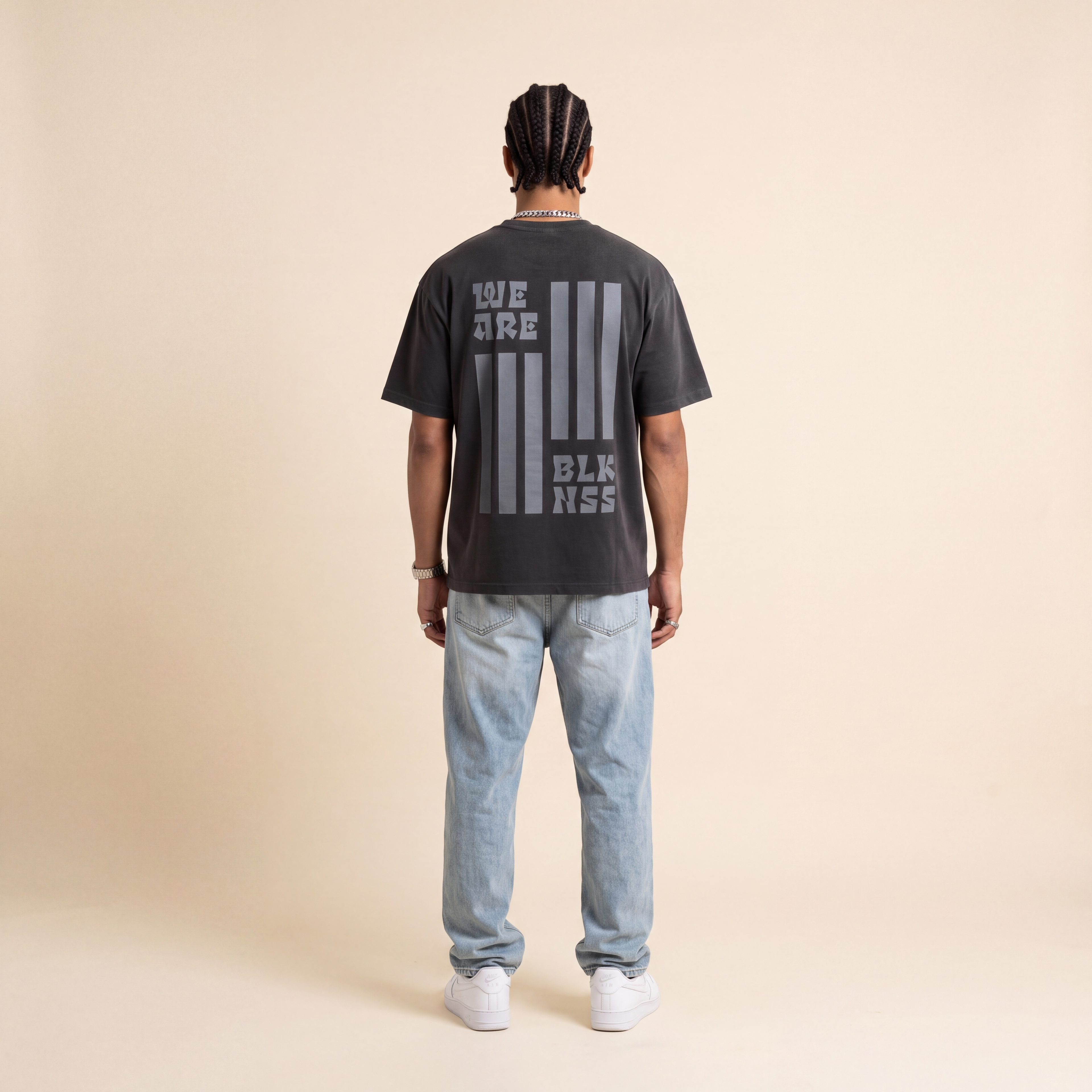 Blackness WABLKNSS Tee Black worn by model, back print view on beige studio backdrop