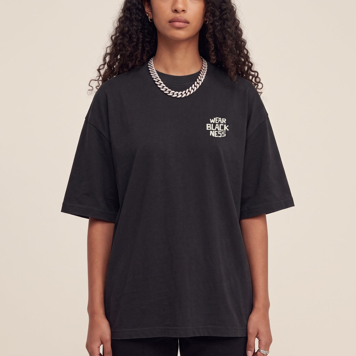 Wear Blackness Tee Black — close-up of the Wear Blackness chest logo and ribbed collar, oversized heavyweight cotton streetwear tee by We Are Blackness