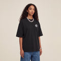 Wear Blackness Tee Black worn by model, front view with Wear Blackness chest print on warm ivory studio backdrop
